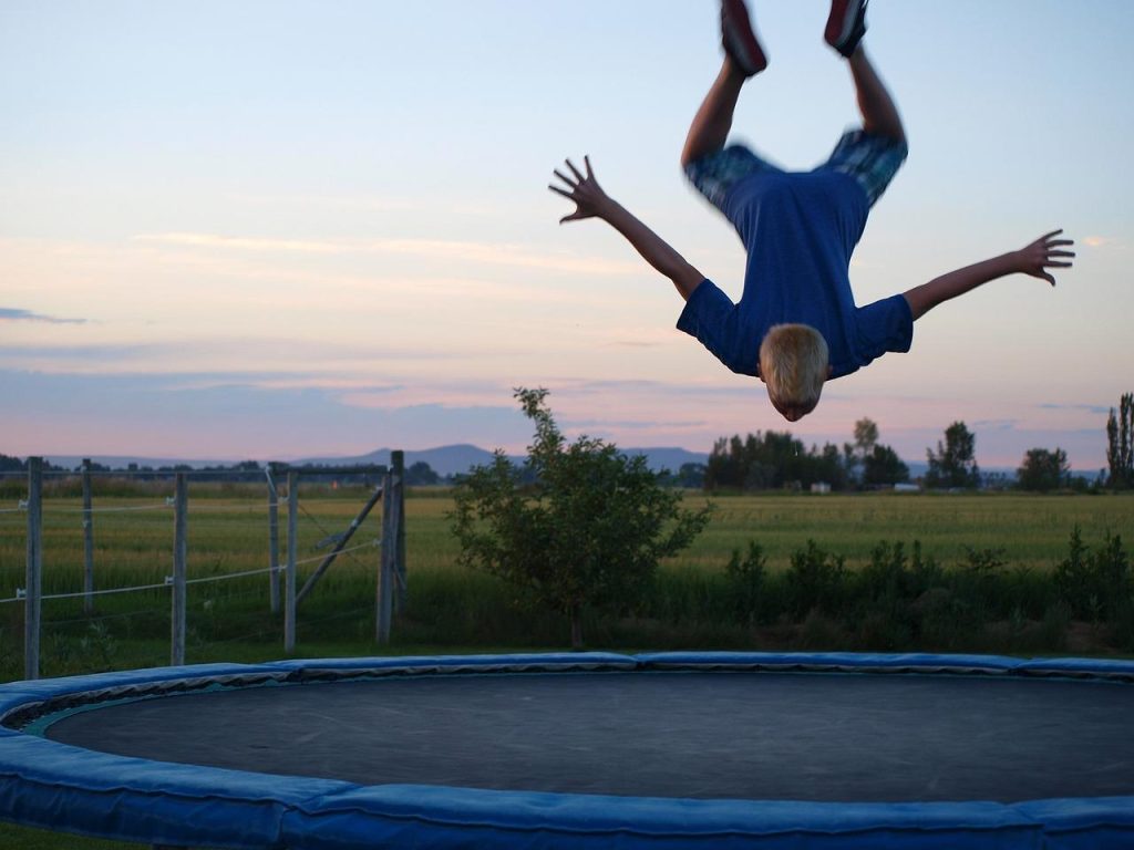Familie speelt samen op een trampoline in de tuin en geniet van de voordelen van trampolinespringen
