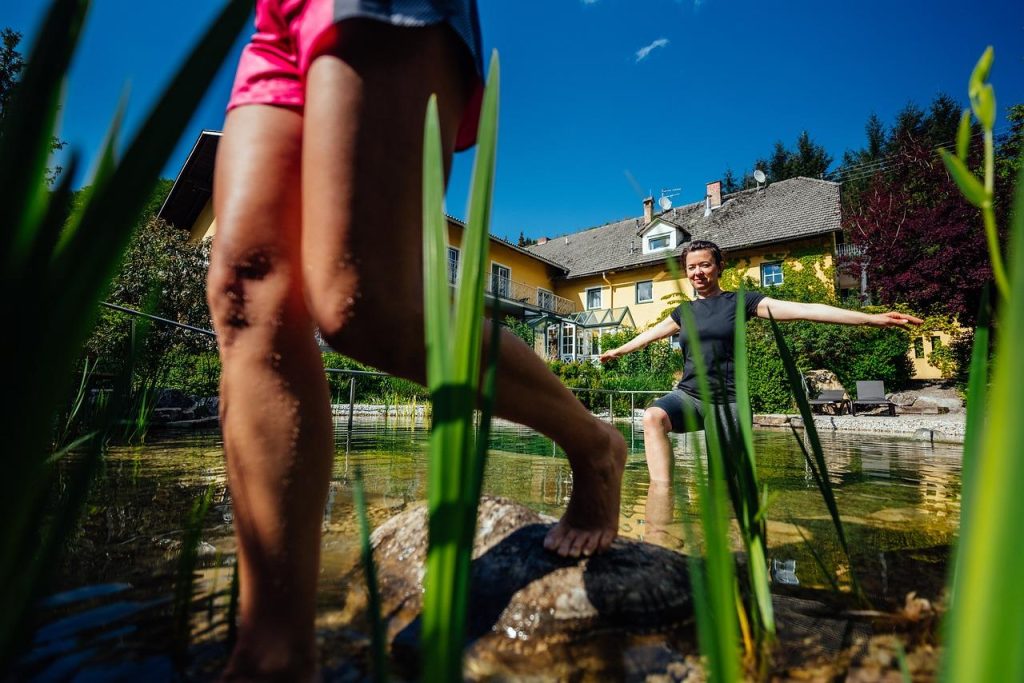 Een mooi aangelegde zwemvijver in een tuin met natuurlijke planten en helder water